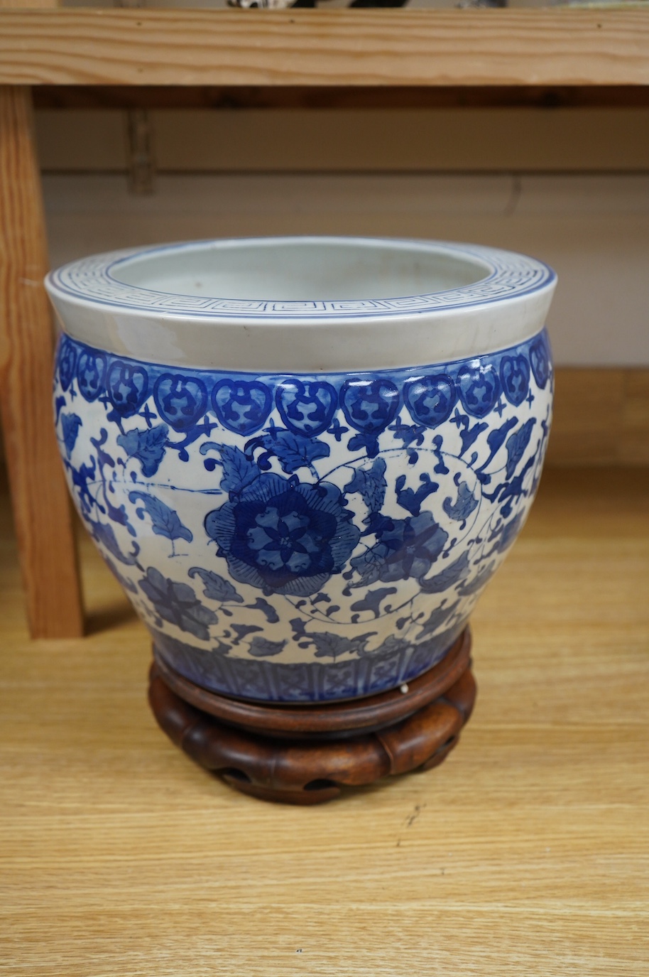 A Chinese blue and white floral jardiniere on hardwood stand, overall 32cm high. Condition - good